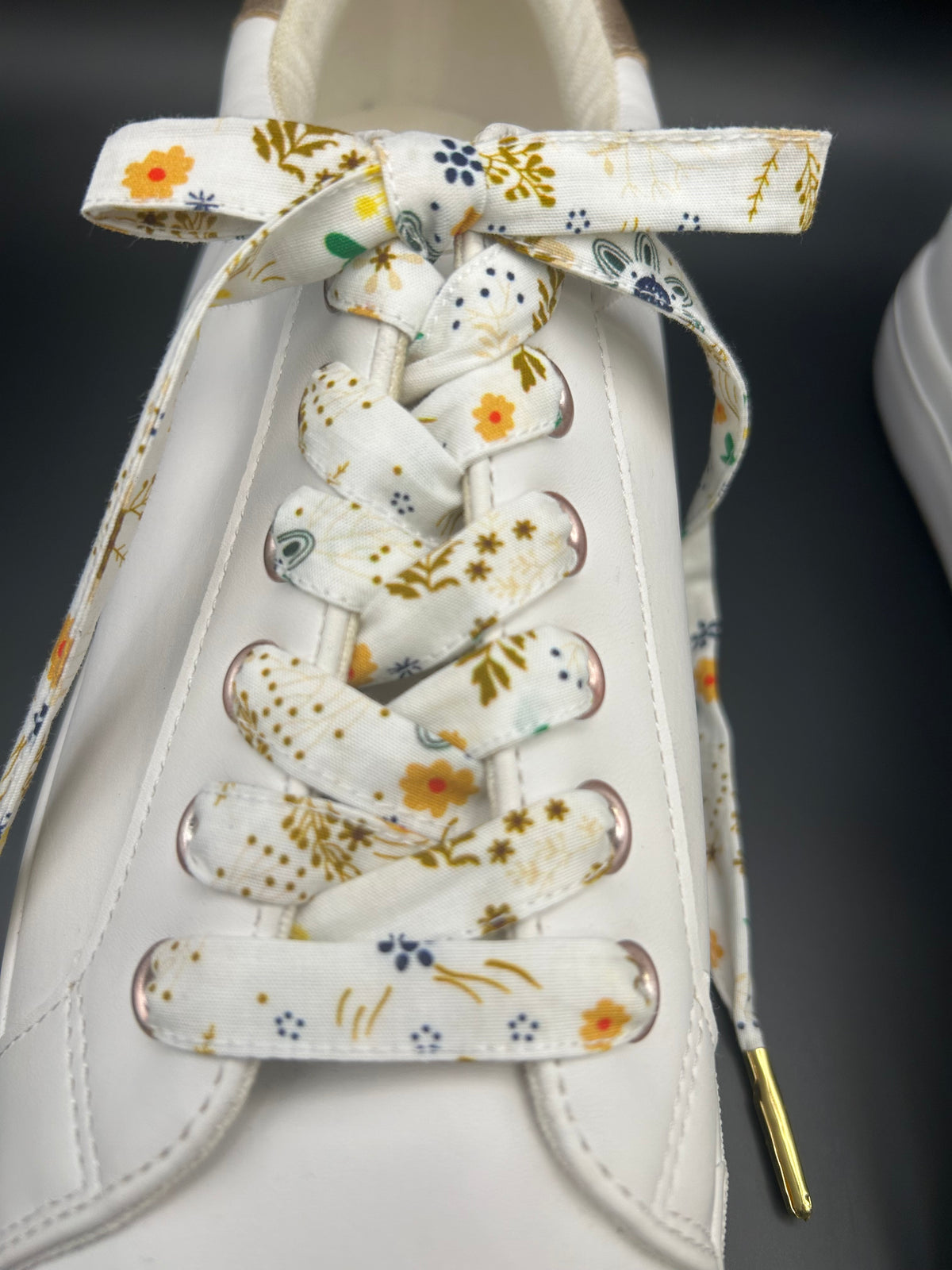 Gros plan sur le nœud d'un lacet en tissu fleuri sur basket blanche