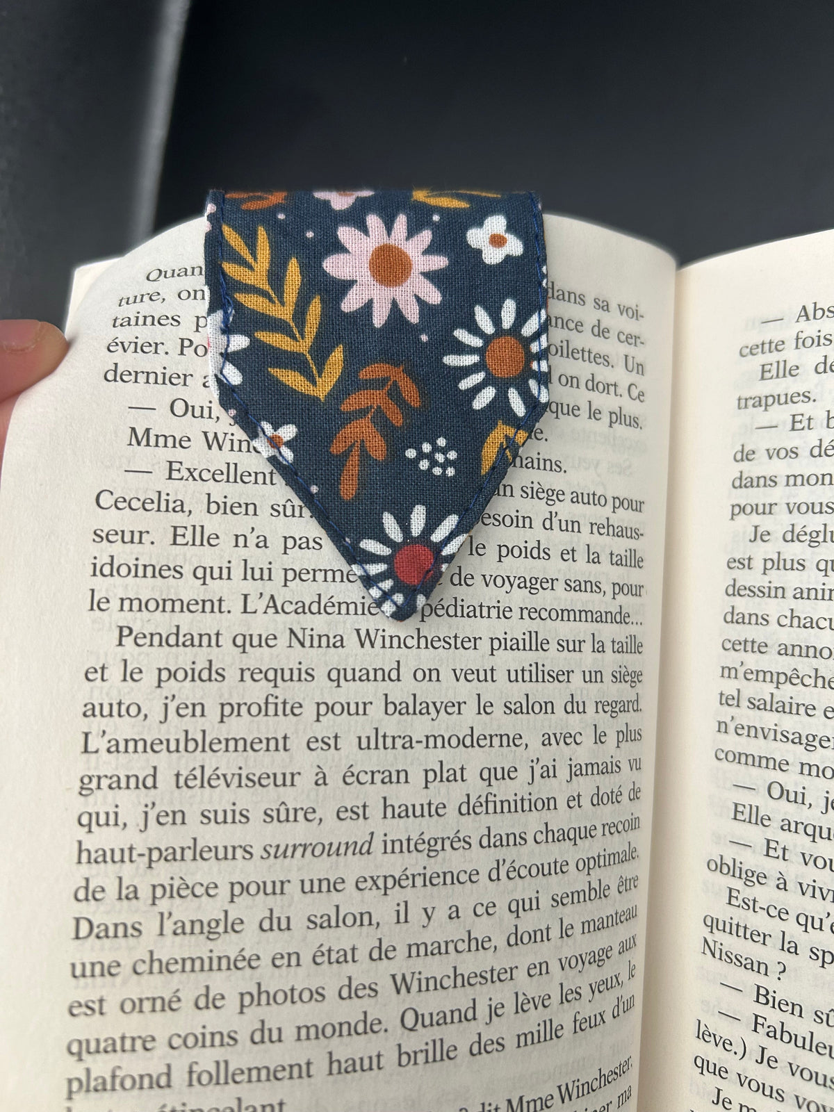 Marque-page aimanté en tissu fleuri bleu marine posé sur une page de roman ouvert