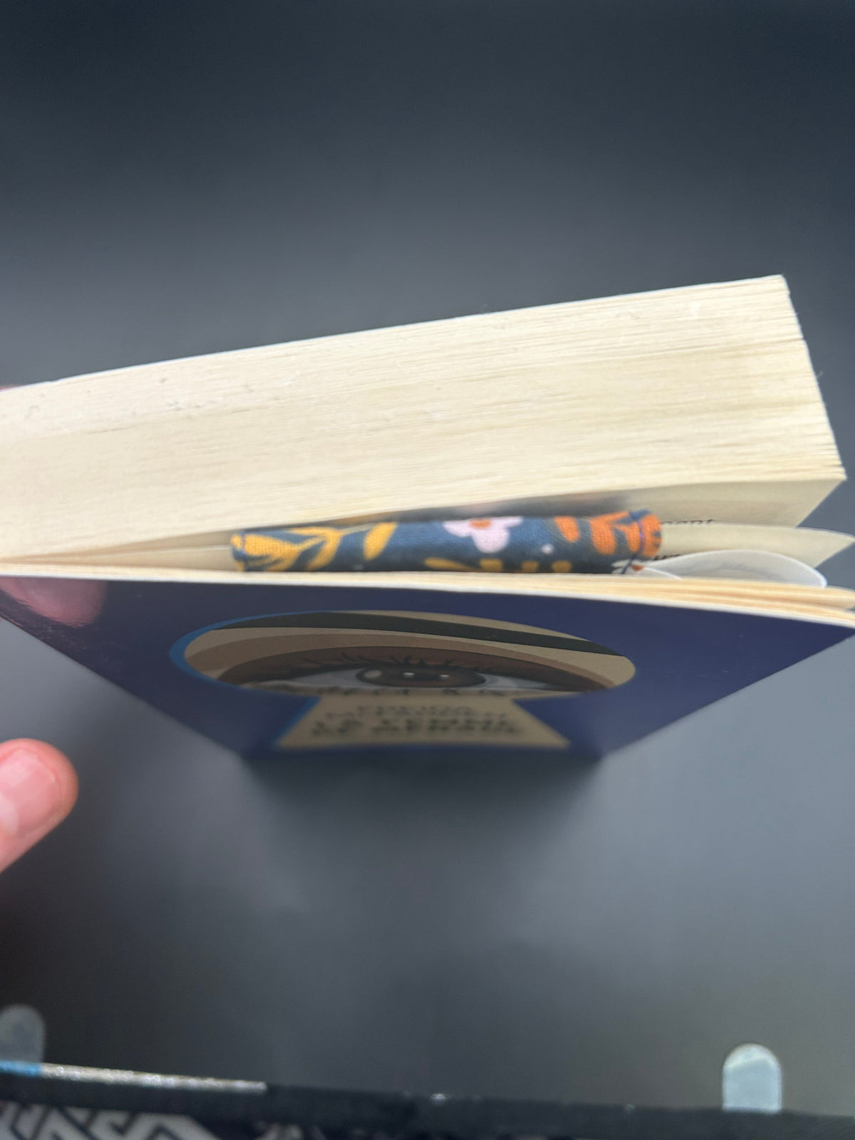  Marque-page aimanté fleuri en tissu glissé entre les pages d'un livre, vu de dessus