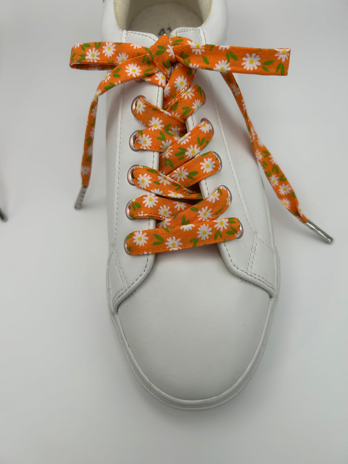 Basket blanche avec des lacets orange à marguerites blanches