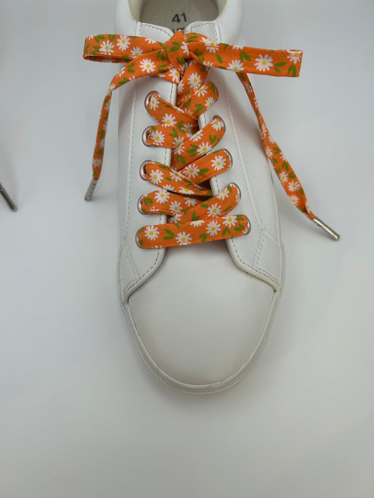 Basket blanche avec des lacets orange à marguerites blanches