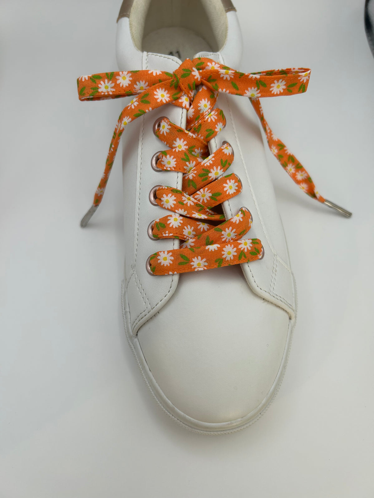  Basket blanche vue de dessus, lacets orange fleuris et embouts métalliques visibles